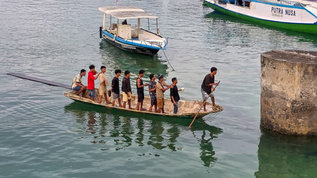 Small boat with men standing beneath the Yellow Bridge in Nusa Lembongan