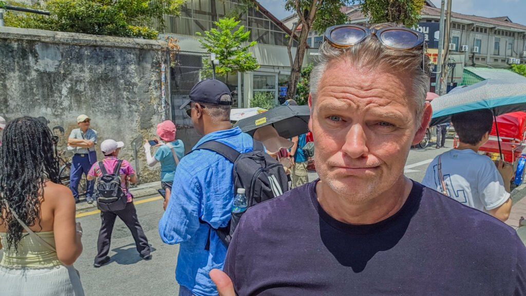 Martin in George Town watching tourists at a popular street art attraction
