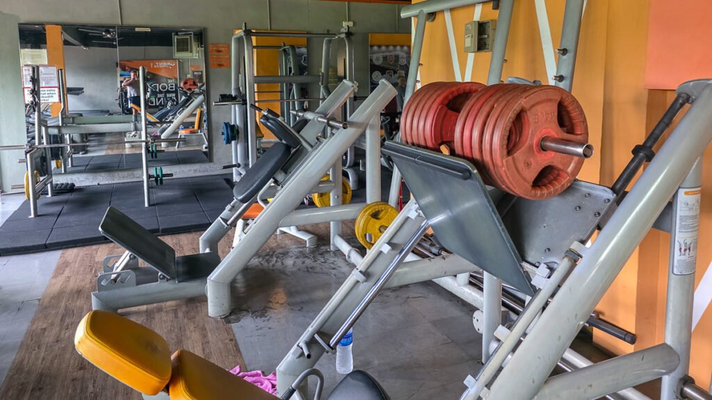 Simple local gym in Penang with basic equipment including a leg press and squat racks