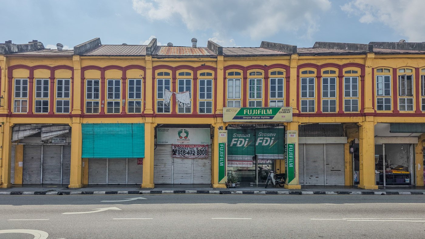 Quiet street in Penang with old colonial-style houses under a blue sky
