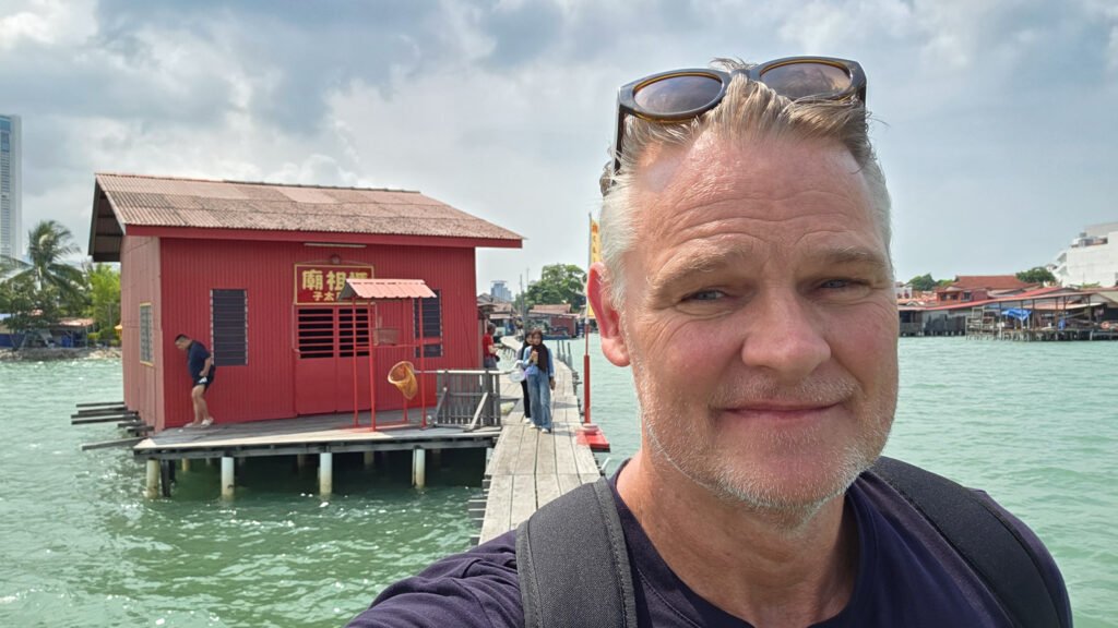 Martin standing at Tan Jetty with the red jetty house in George Town, Penang