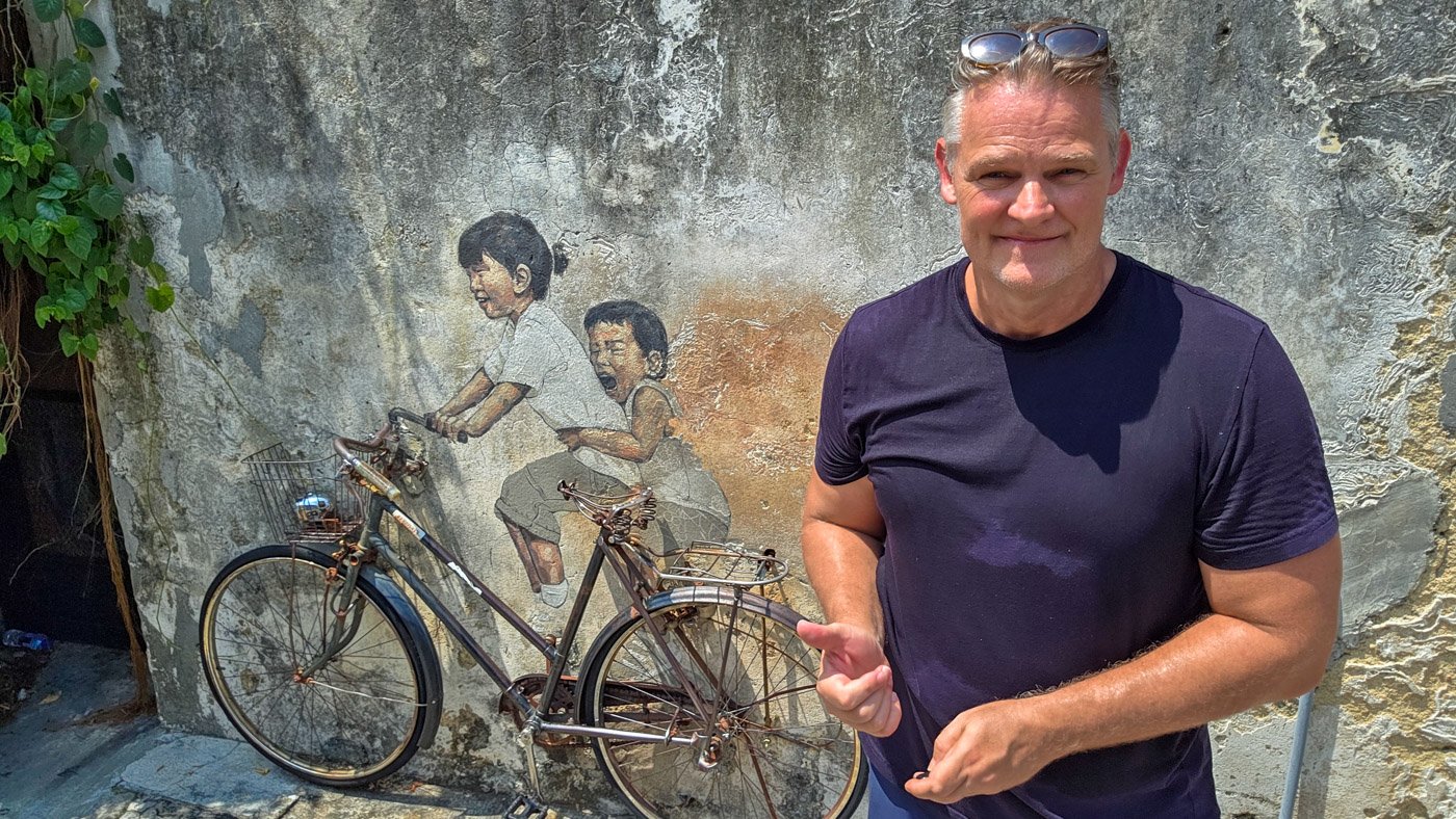 Martin standing beside the famous bicycle mural in George Town, Penang
