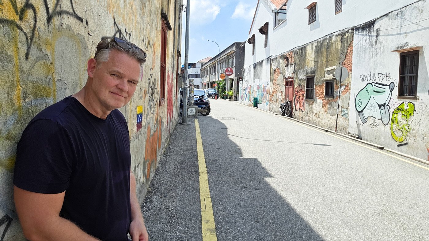 Martin standing against a wall in a quiet street in George Town, Penang