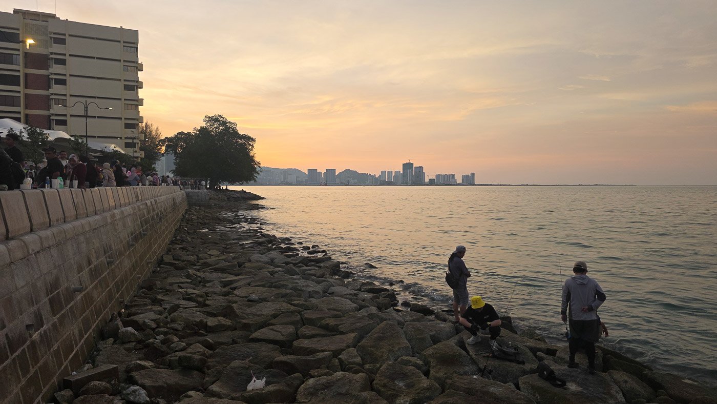 Sunset at the Penang waterfront with fishermen and the George Town skyline in the background