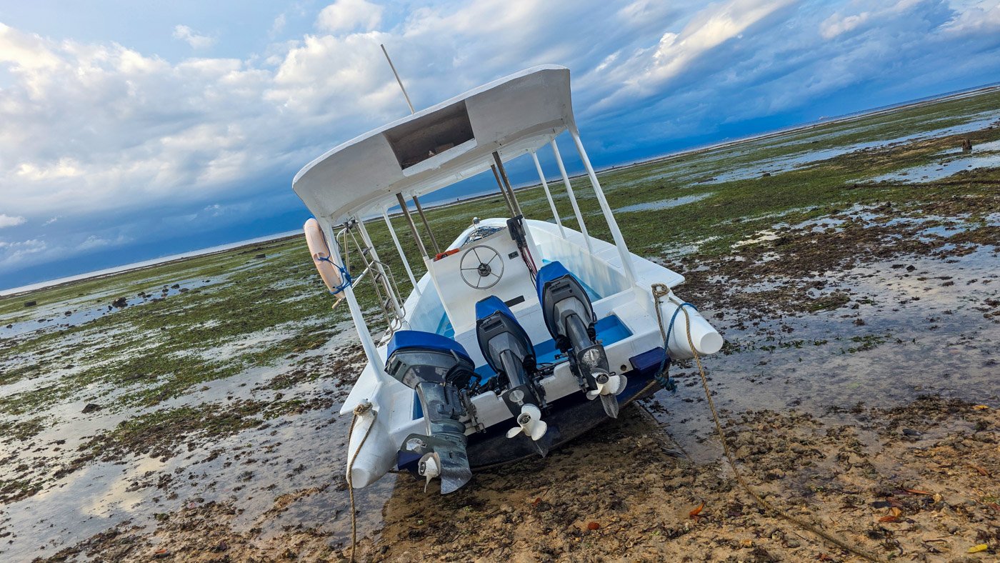 Small boat resting on the shoreline during low tide in Nusa Lembongan.