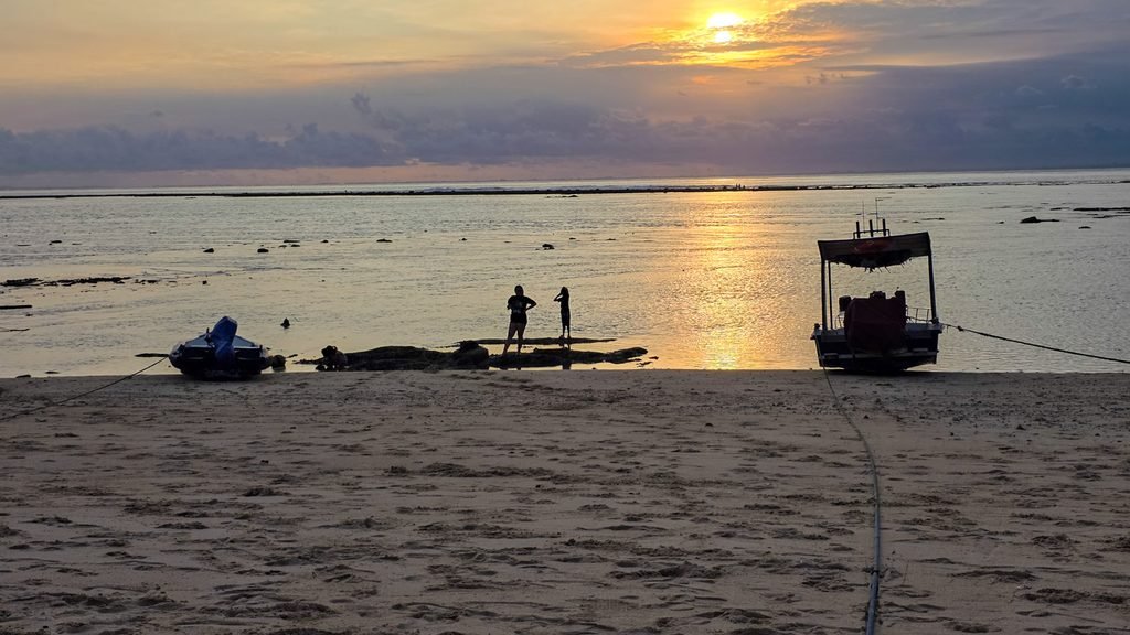 Locals searching for shellfish and seafood on exposed reef flats during low tide in Nusa Lembongan