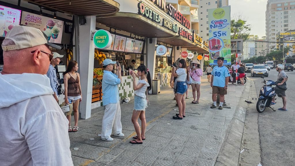 Young Vietnamese photographers creating portraits in Da Nang as a foreign visitor walks into the scene