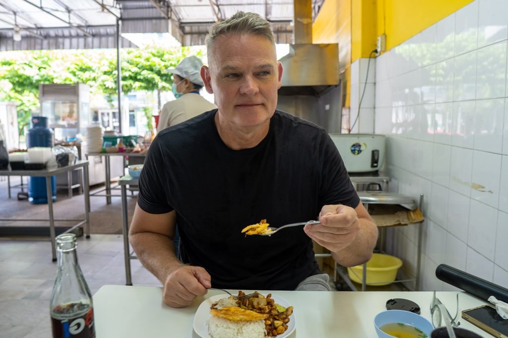 Martin Gram having lunch at a neighborhood Thai eatery in Bangkok while looking out toward the street.