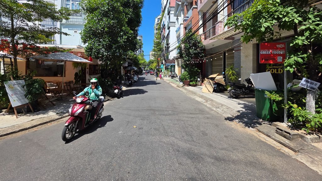 Grab motorcycle driver riding through a quiet residential street in Da Nang, Vietnam.