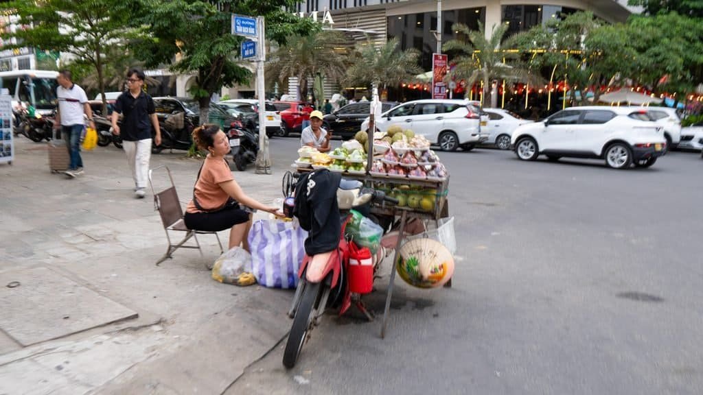 Fruit vendor on a Da Nang street with traffic and buildings in the background