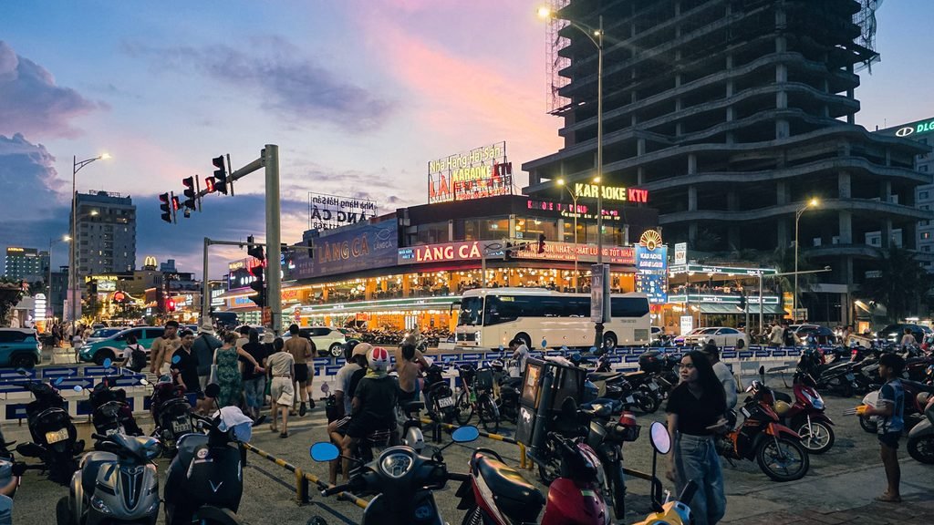 Evening traffic, scooters, and restaurants along a busy street near Da Nang Beach, Vietnam.